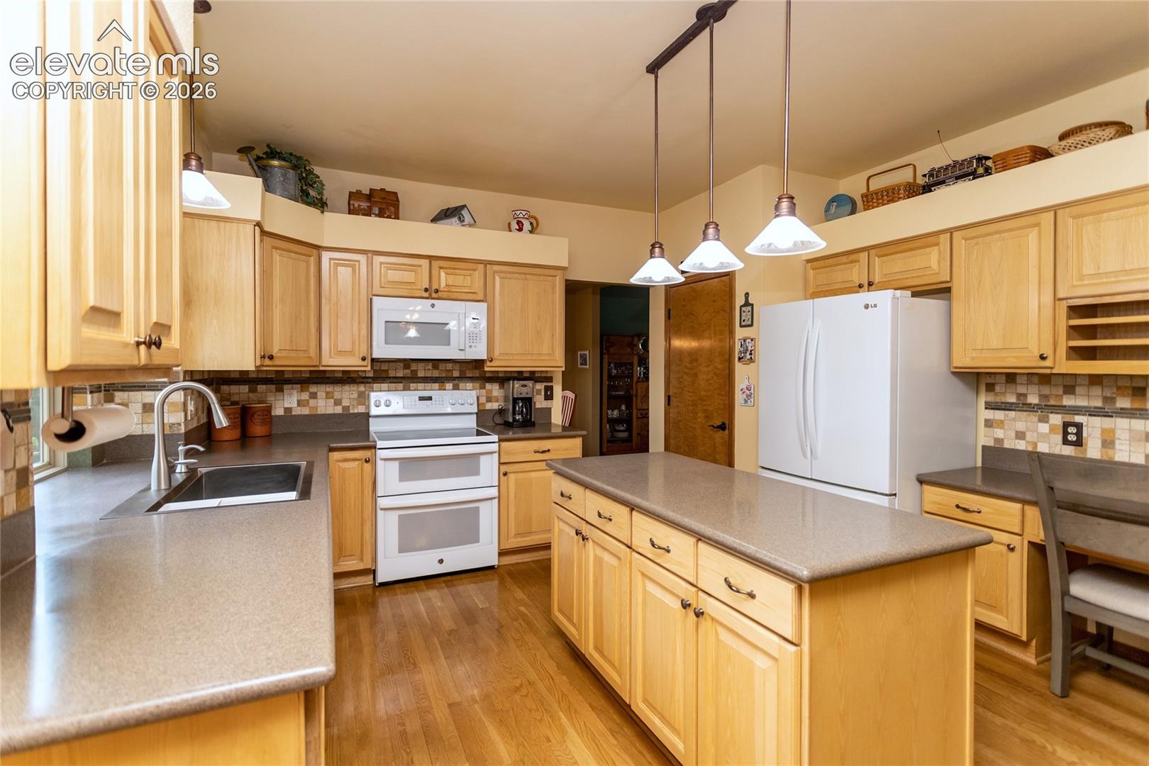 Kitchen adjoins the Family Room and has Hardwood Floors and Solid Man-made Countertops throughout. Features include Double Glasstop electris Range/Oven, Refrigerator, Disposal and Stainless Steel Sink