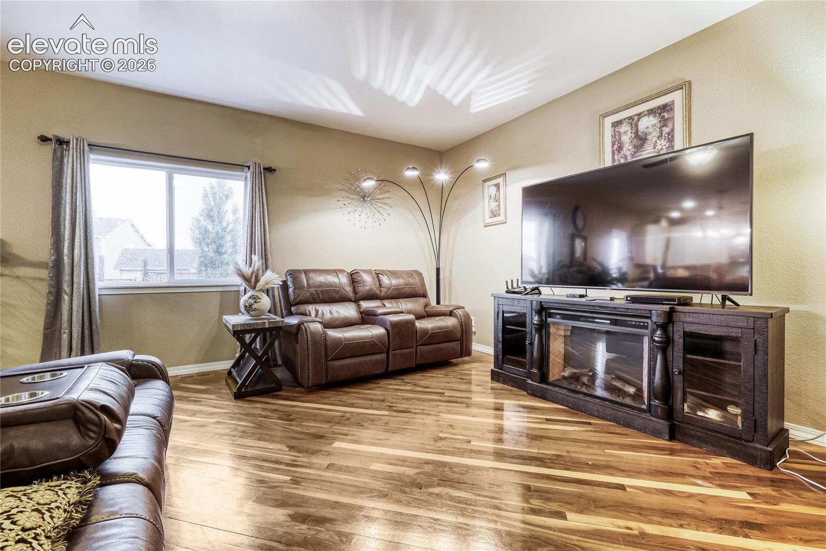 Spacious living area featuring wood flooring, a large picture window, and neutral wall tones