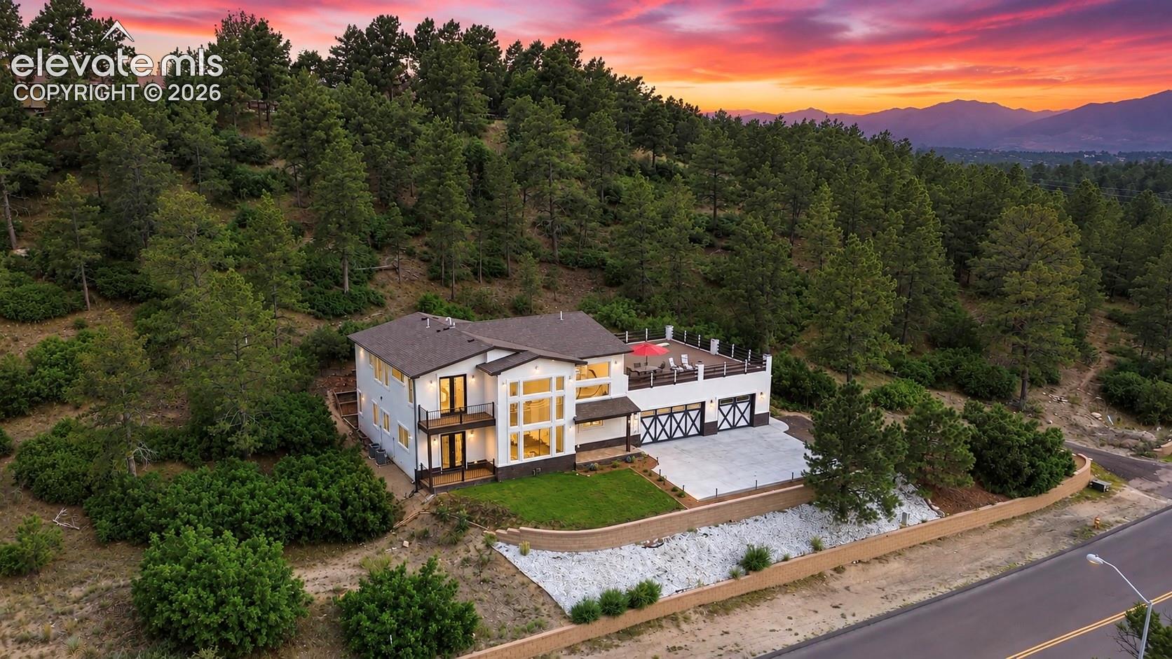 Modern exterior featuring a two-story design, multiple balconies, an upper-level terrace, and a two-car garage with X-brace detailing