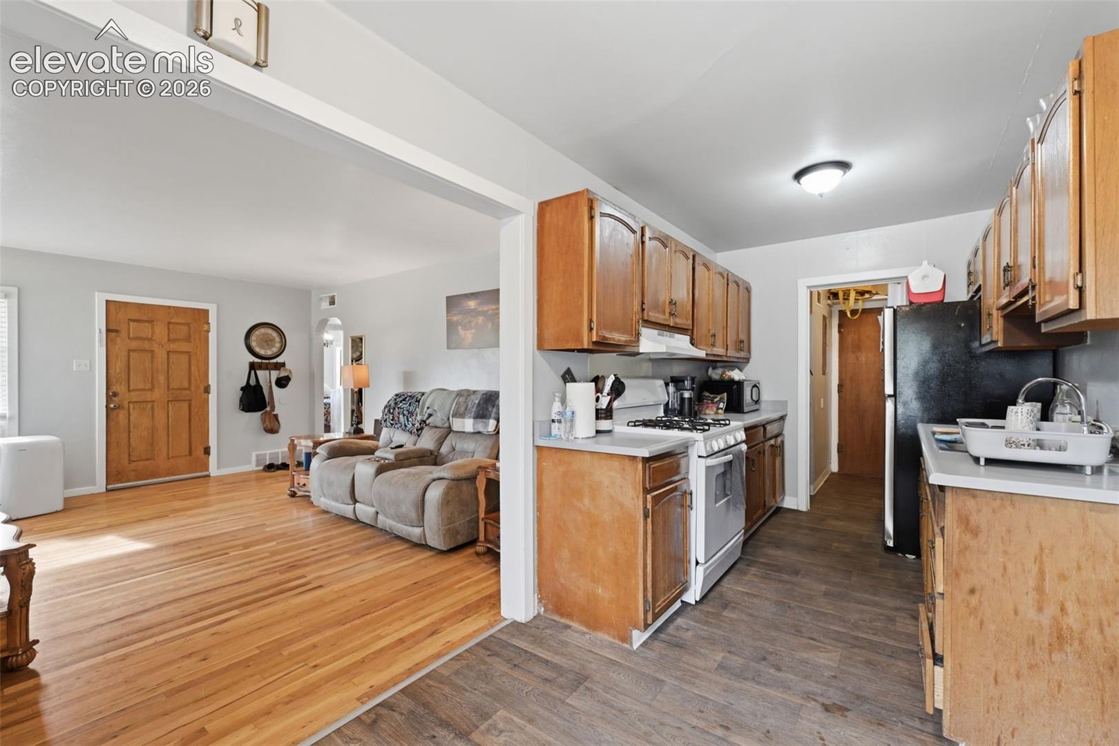 Kitchen with wood cabinetry, light countertops, and wood-finish flooring