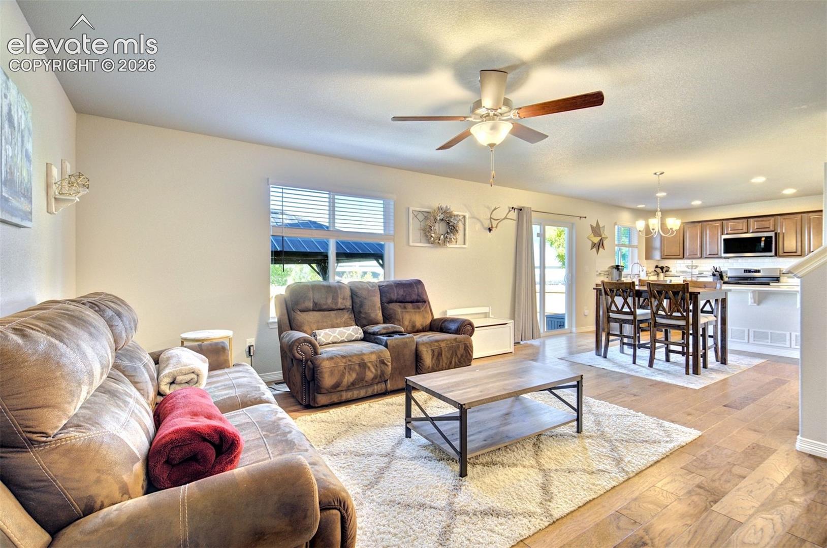 Open-concept interior featuring wood-finish flooring, a kitchen island with bar seating, recessed lighting, a ceiling fan, and sliding glass doors