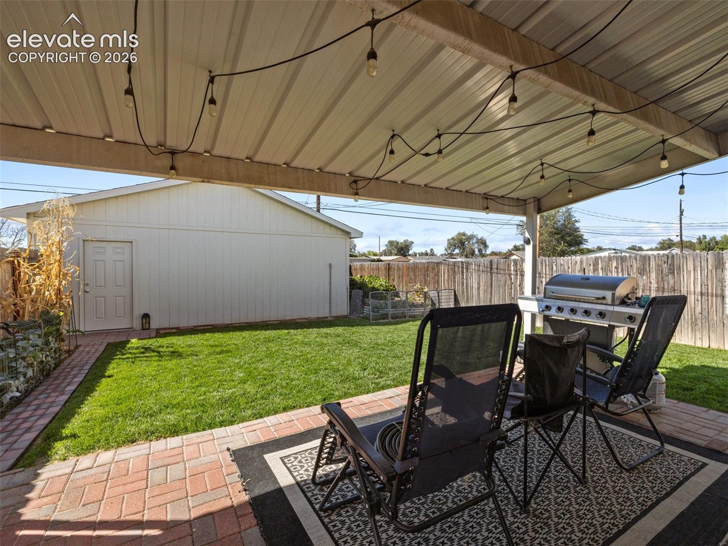 Expansive covered patio with string lighting and brick paver flooring