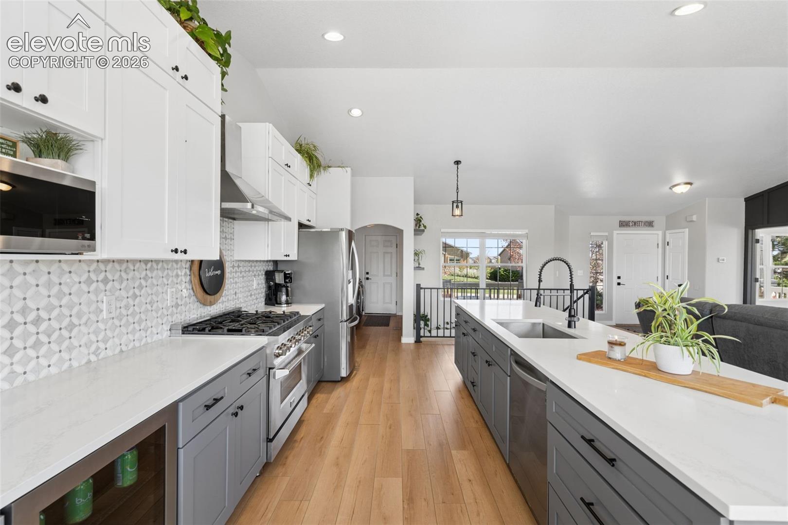 Gourmet kitchen with two-tone cabinetry, stainless steel appliances, and a central island featuring an undermount sink and matte black faucet