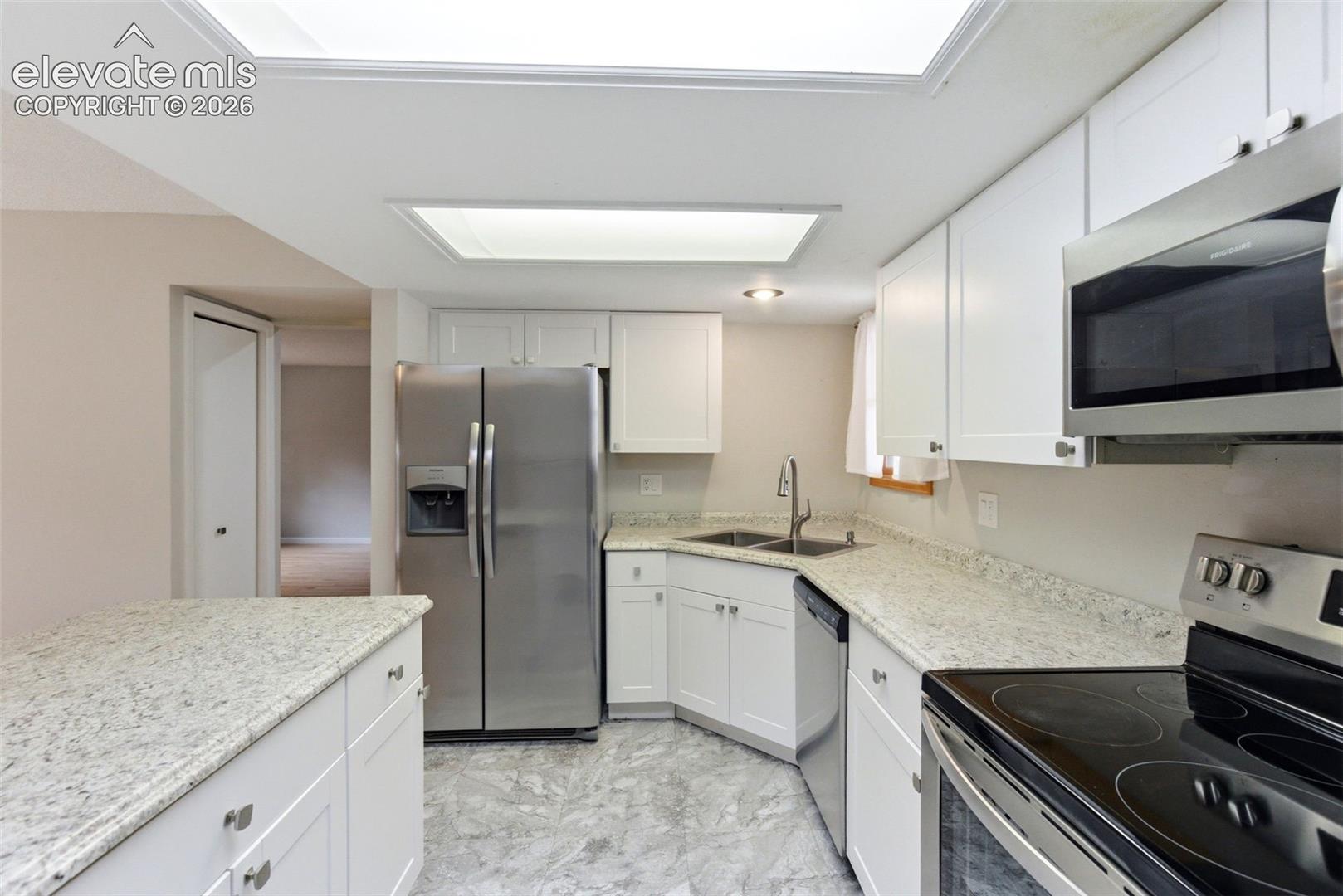 Kitchen featuring white cabinetry, light-toned countertops, recessed lighting, and stainless steel appliances