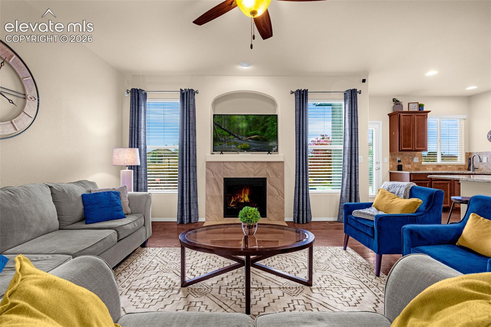 Fireplace featuring a stone-tile surround and recessed arched alcove, wood-finish flooring, and ceiling fan