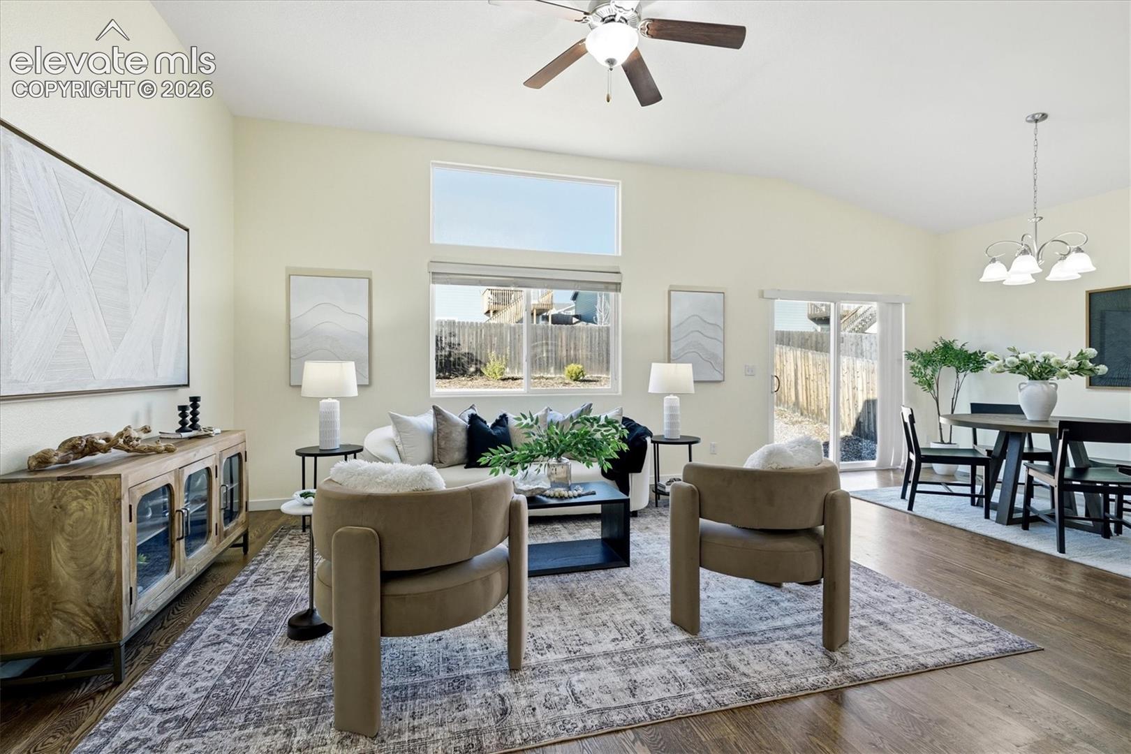 Vaulted ceiling with a ceiling fan, wood-finish flooring, multiple windows, and a sliding glass door