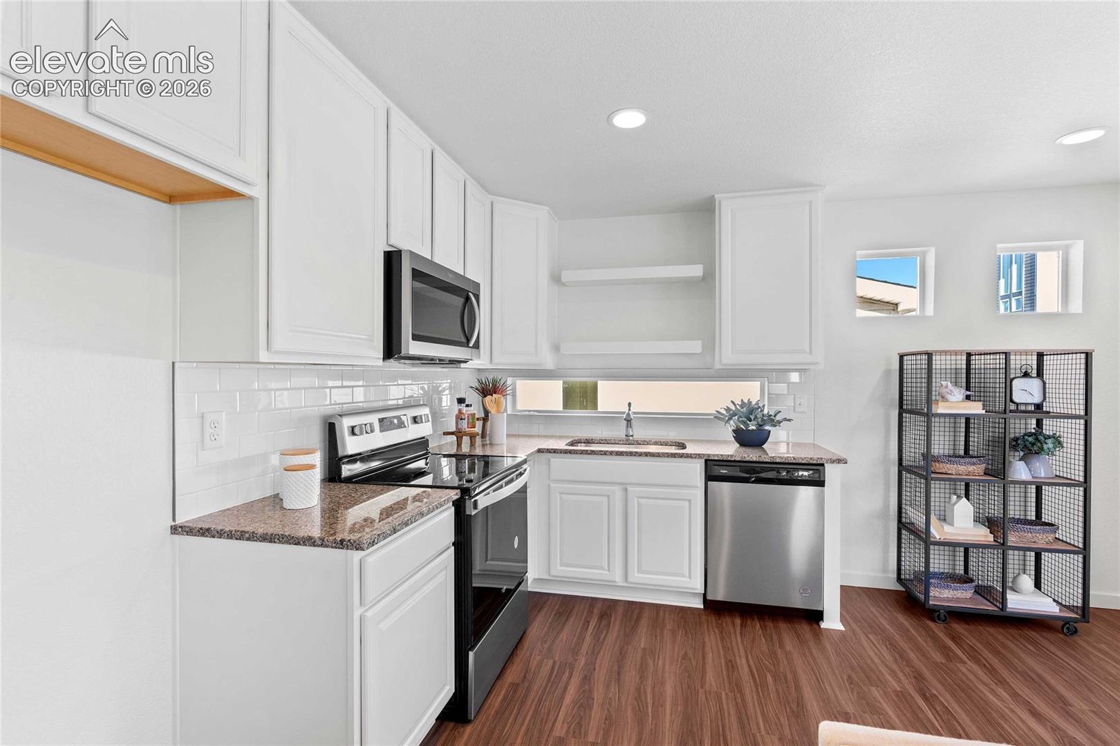 White shaker cabinetry, dark wood-finish flooring, undermount sink, stainless steel appliances, and white subway tile backsplash
*photos of a model home*