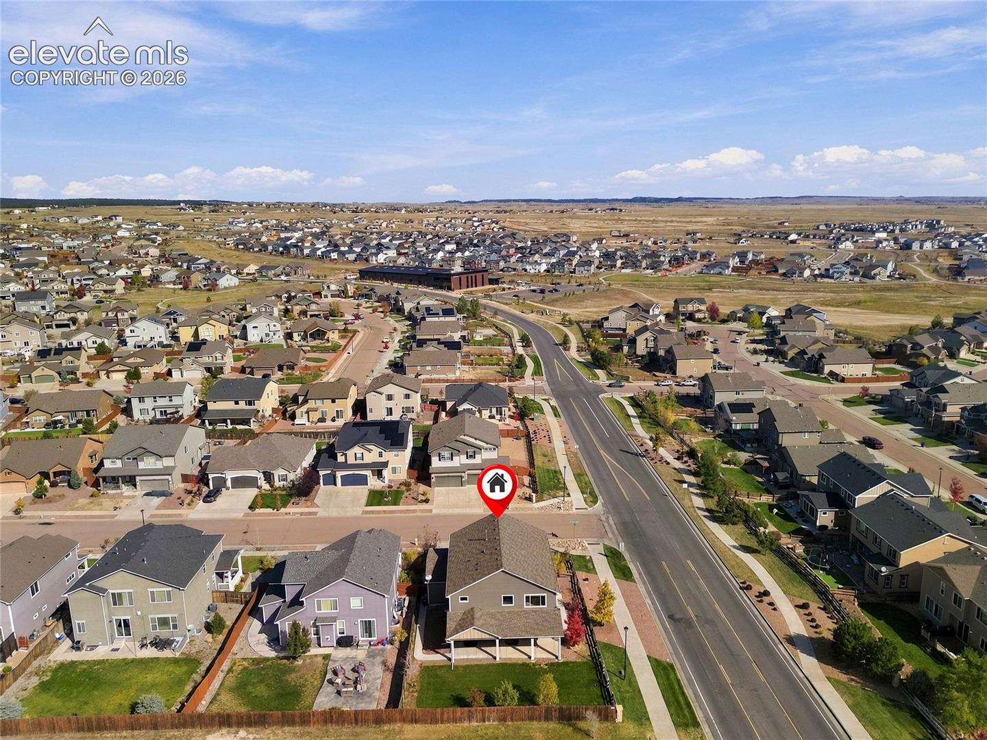 Aerial perspective of a detached residential property featuring a shingle roof, rear-covered patio, and fenced backyard