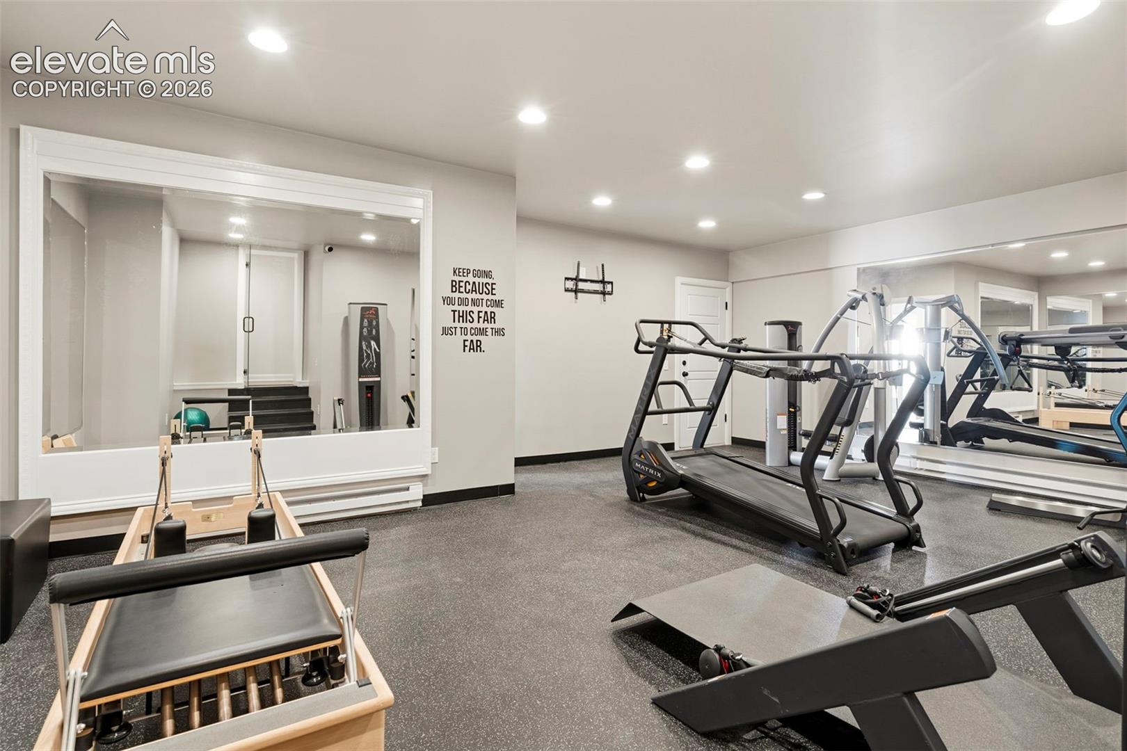 Dedicated fitness space featuring wall-to-wall mirrors, recessed lighting, and resilient rubberized flooring