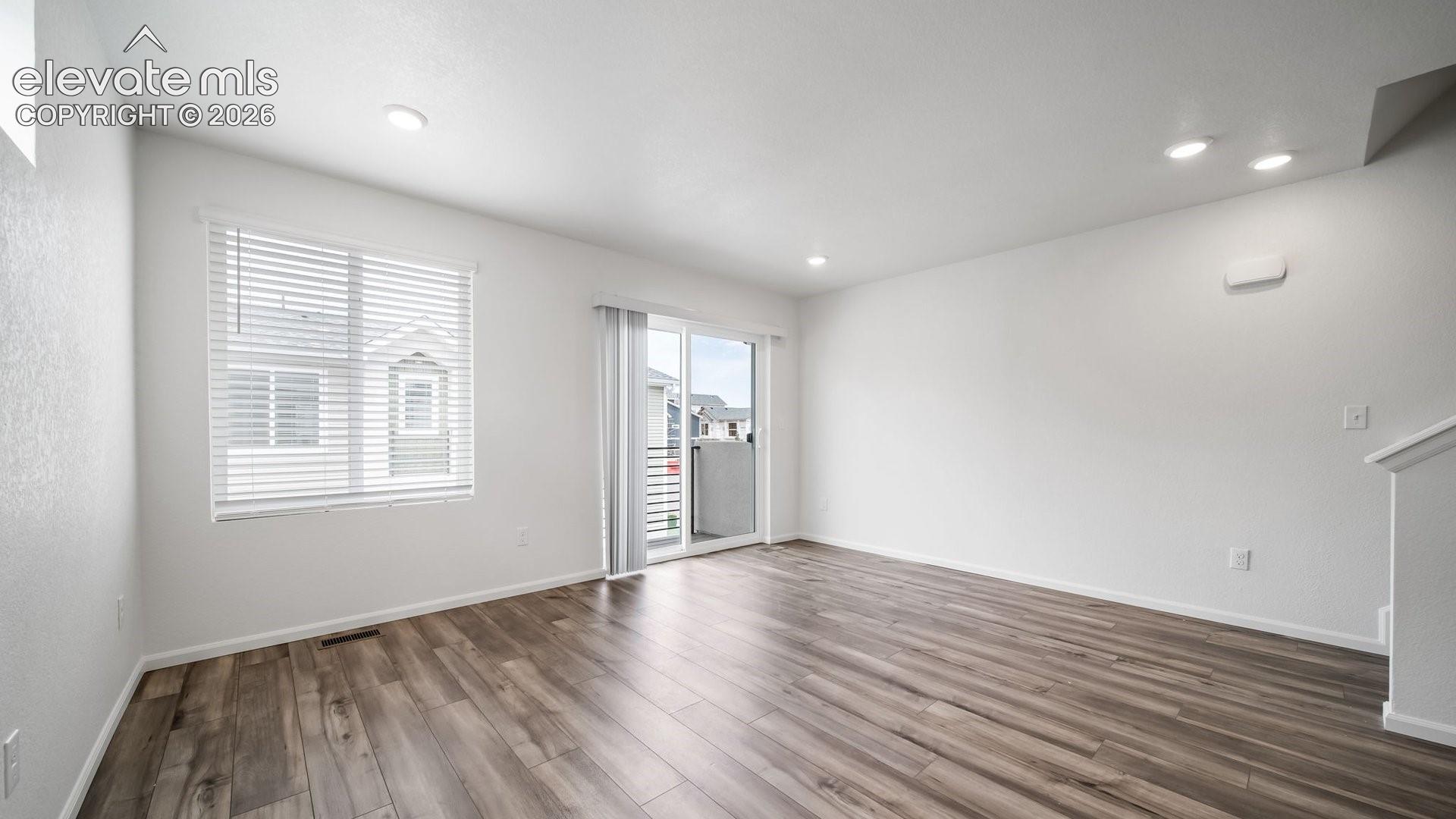 Expansive room featuring wood-finish flooring, recessed lighting, and a sliding glass door to a balcony
*photos of a model home*