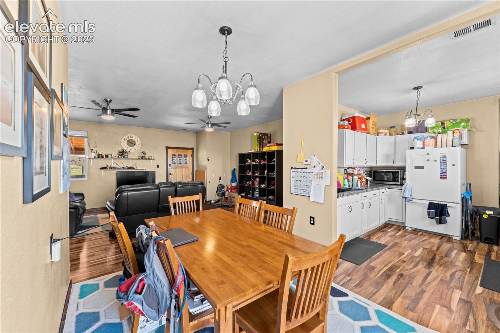 Wood-finish flooring throughout, multi-arm chandelier lighting, and white cabinetry