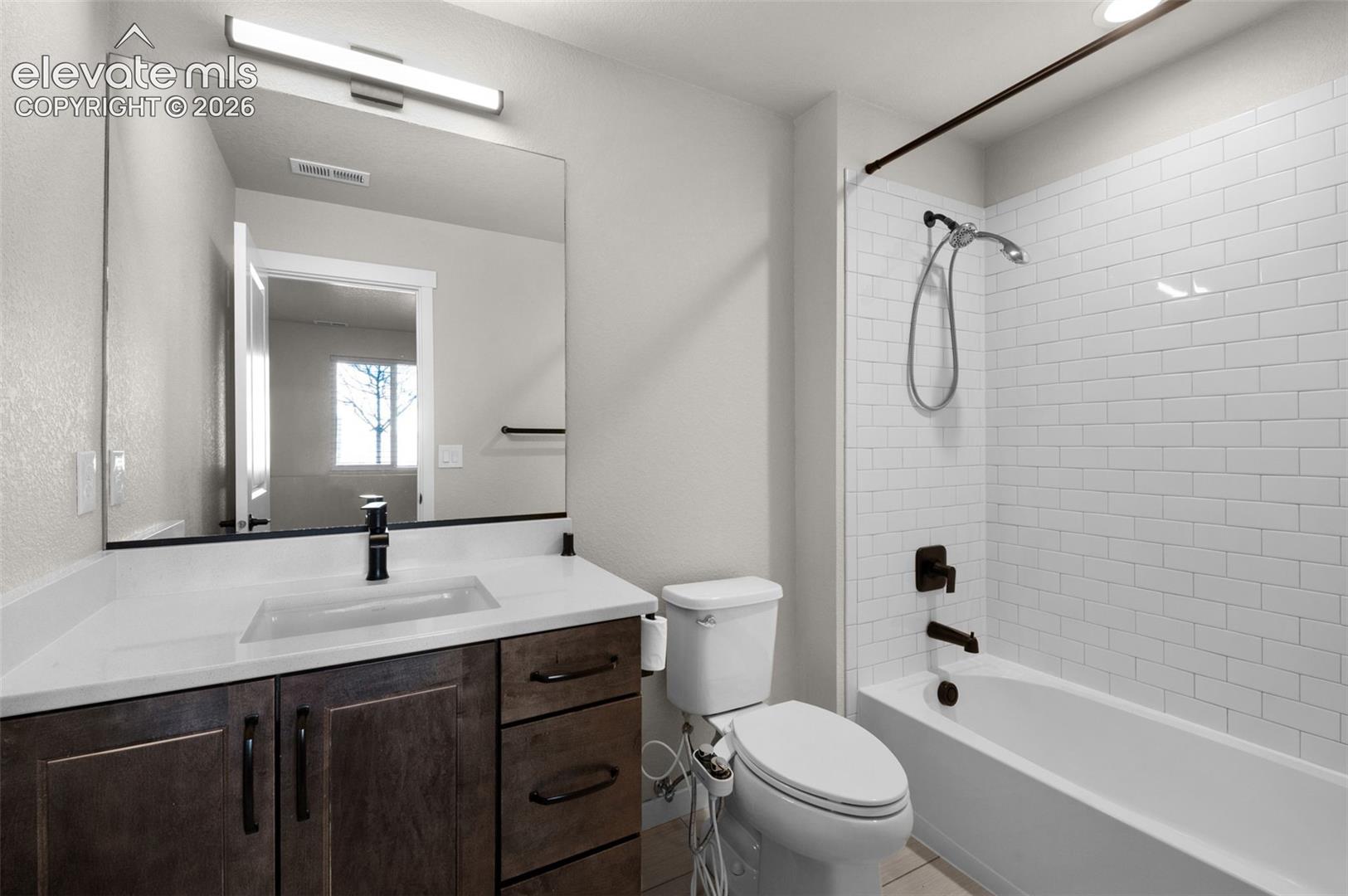Wood-finish vanity with an integrated sink, white countertop, and matte black faucet