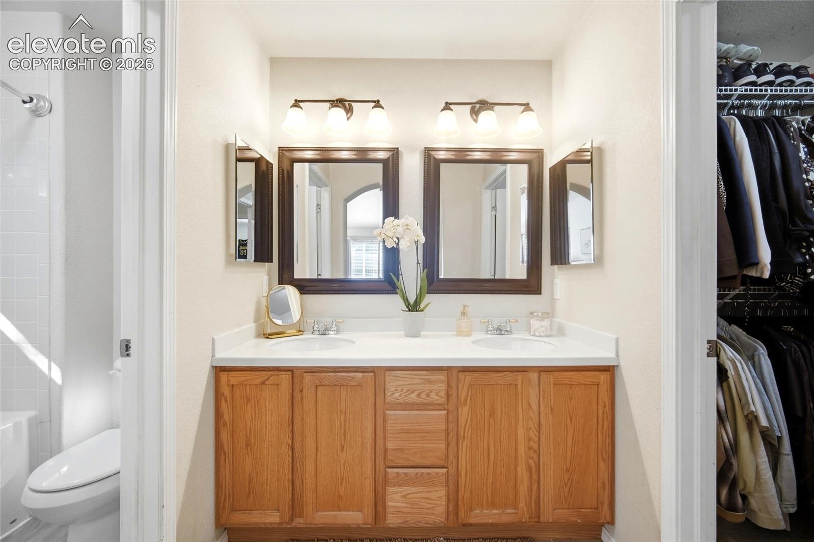 Double vanity with wood-finish cabinetry, dual sinks, and individual framed mirrors
