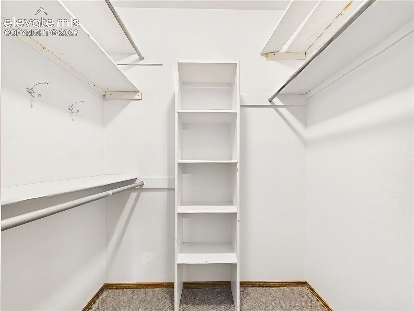Spacious walk-in closet with built-in shelving and multiple hanging areas to keep wardrobes neatly organized.