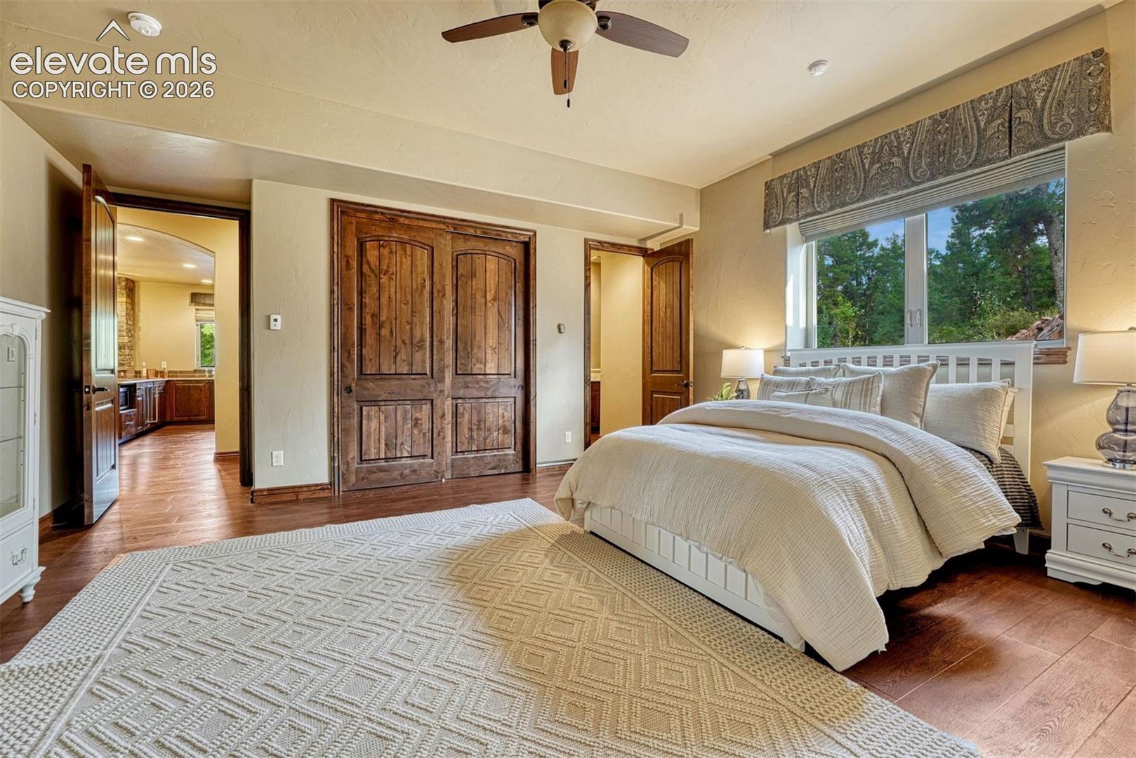 Wood-finish flooring, paneled wood closet doors, and a ceiling fan