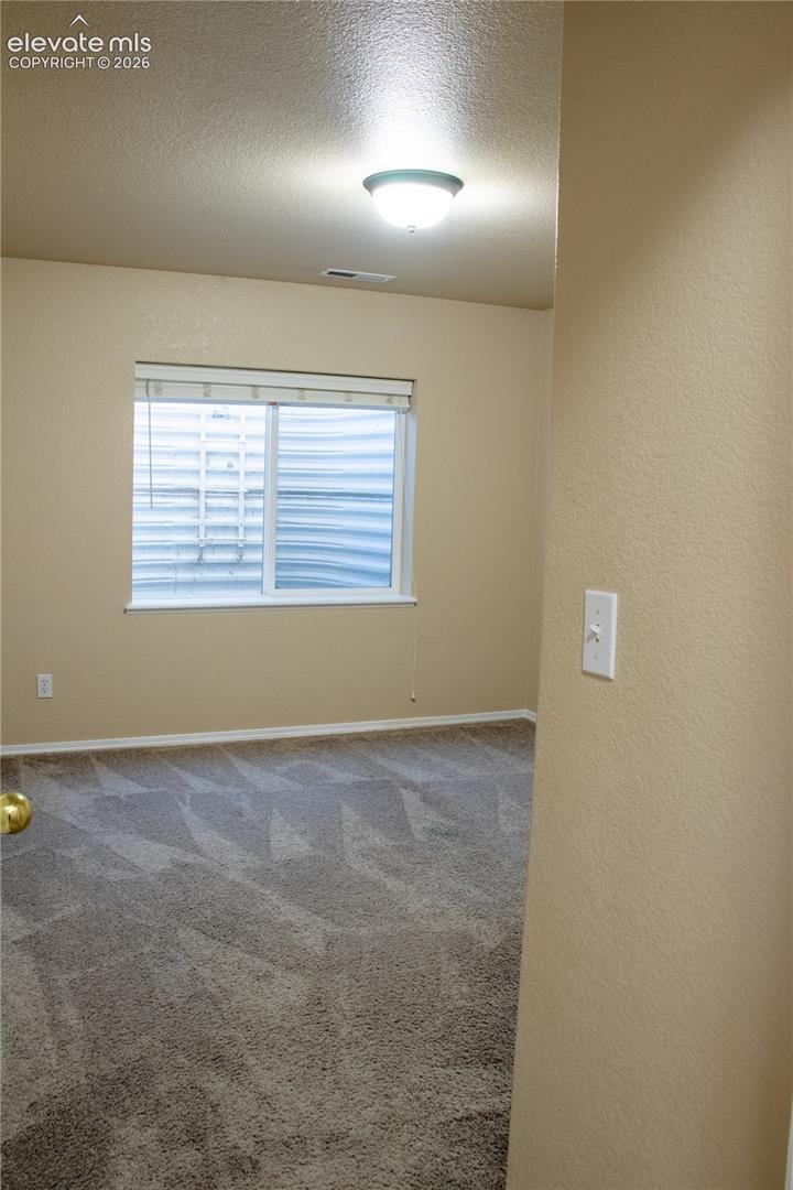 Interior room featuring neutral wall paint, a single window with blinds, and flush-mount ceiling lighting