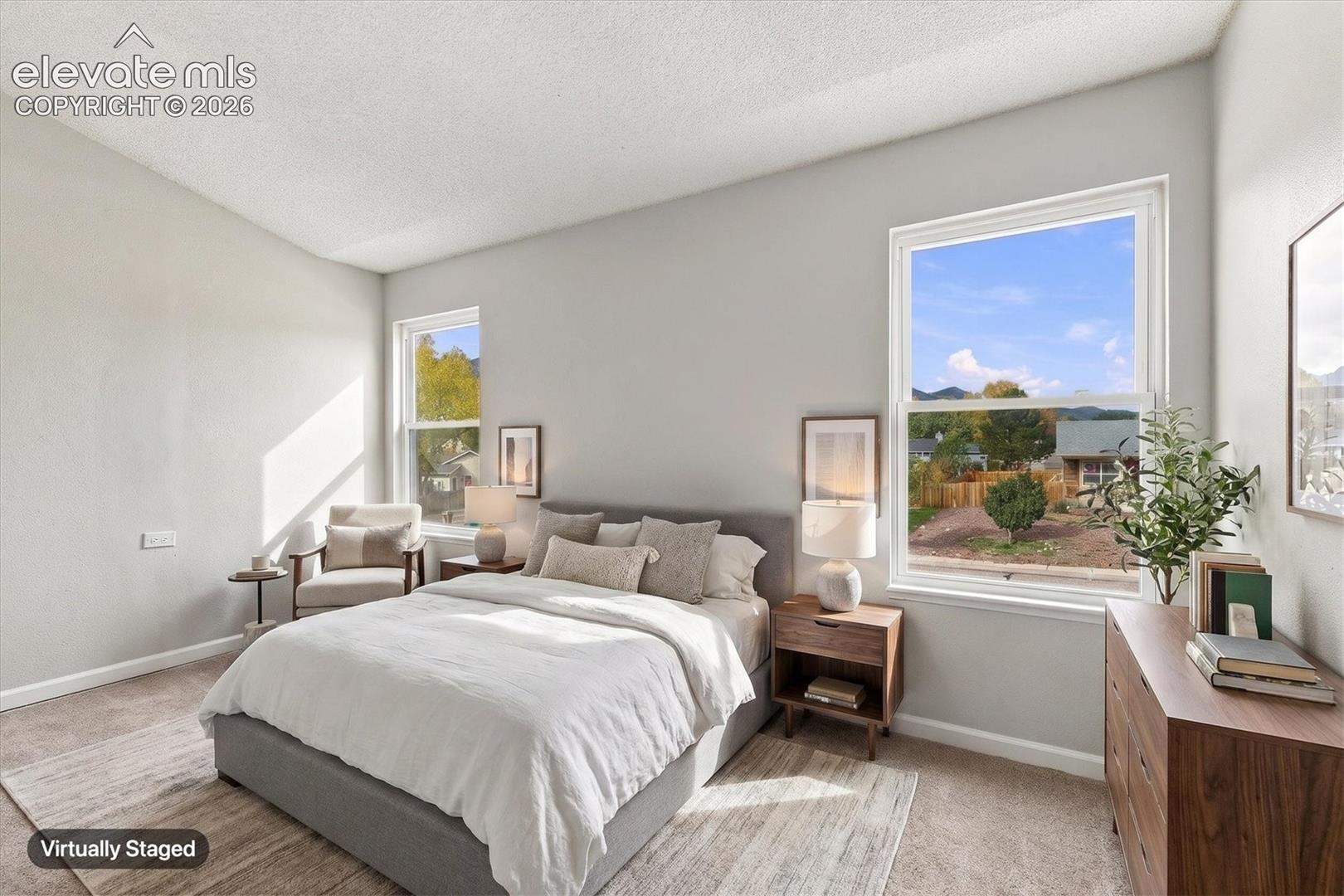 Bedroom featuring vaulted ceilings, neutral wall tones, carpeted flooring, and dual windows with mountain scenery