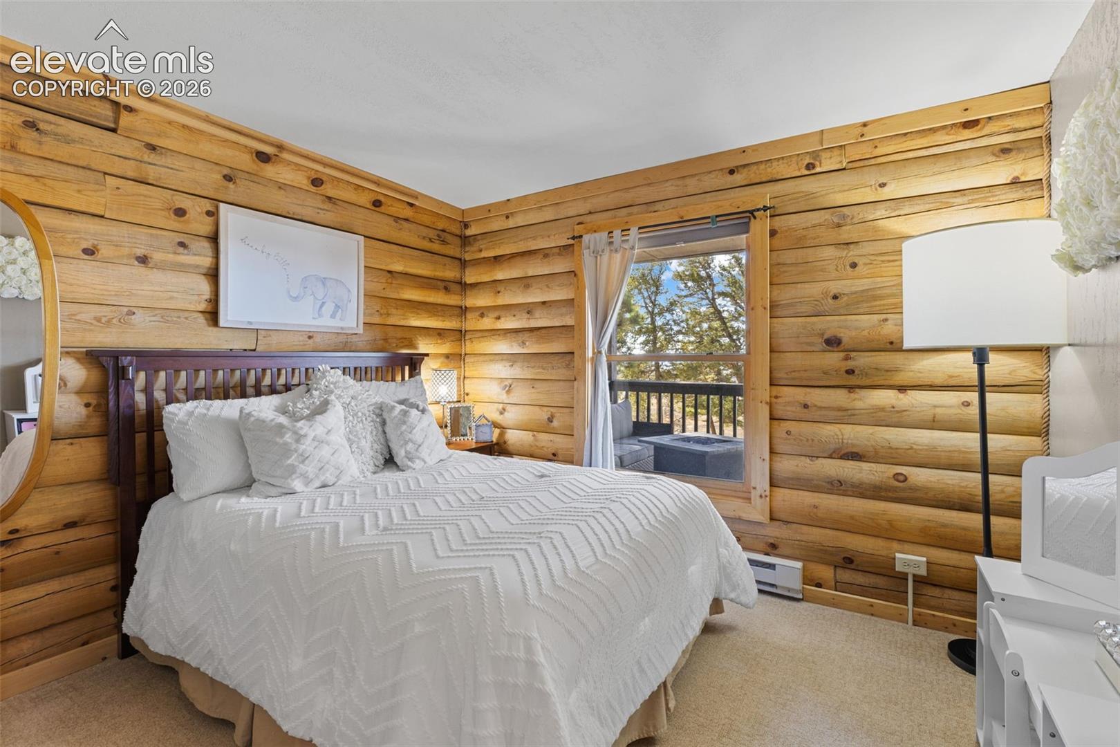 Room featuring horizontal log wall construction, natural finish wood wall textures, and an exterior egress providing natural lighting