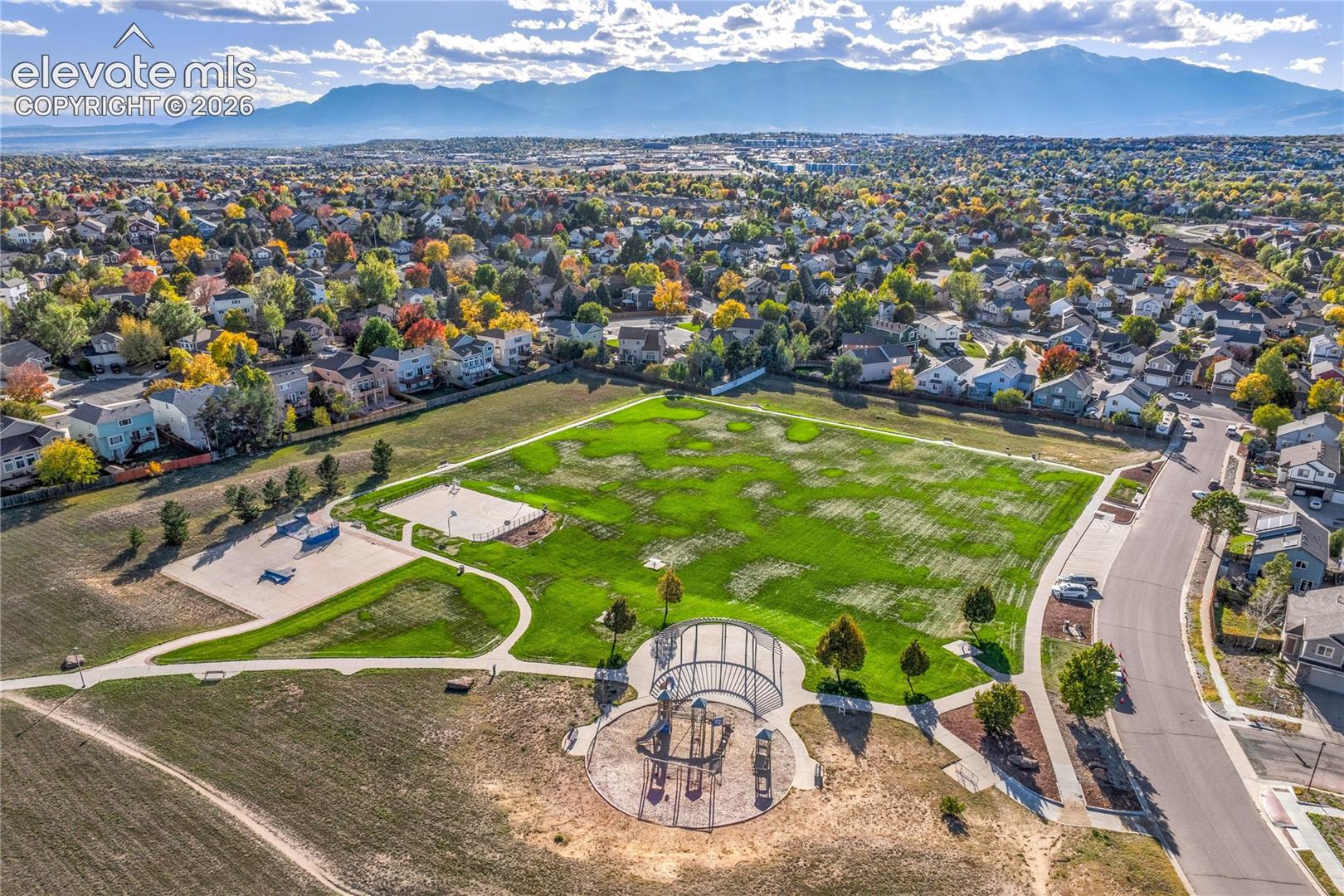 Aerial views showcase neighborhood recreation areas, winding pathways + open green space, with the Front Range and Pikes Peak providing a scenic Colorado backdrop.