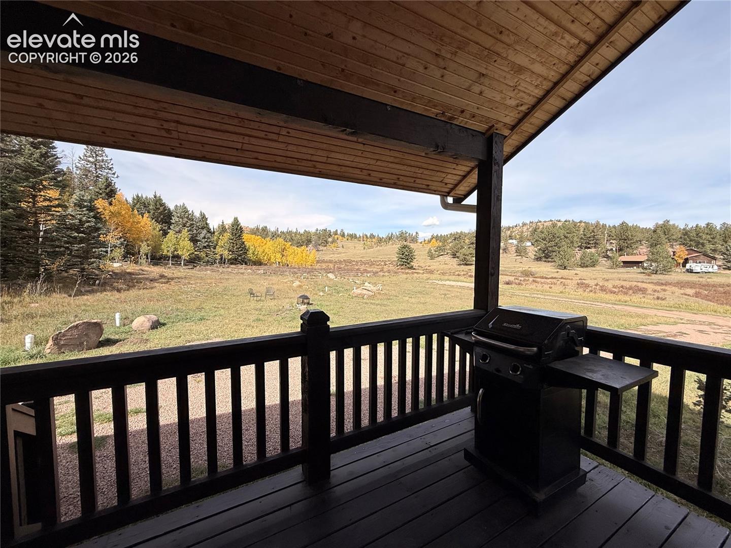 Covered wood-plank deck with wood railing, featuring a vast natural landscape backdrop