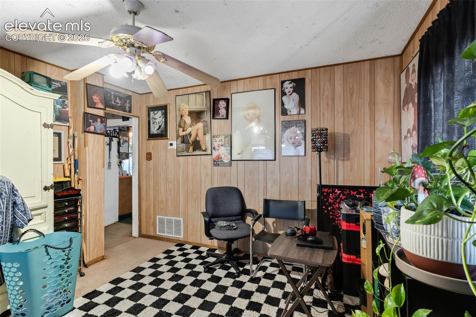 Wood paneling throughout, ceiling fan with integrated lighting, and a neutral carpeted floor