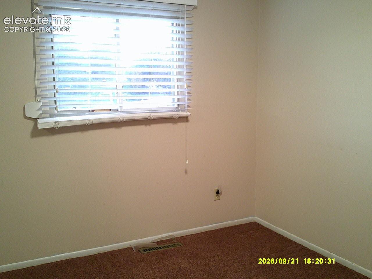 Neutral-toned walls with a window featuring horizontal blinds