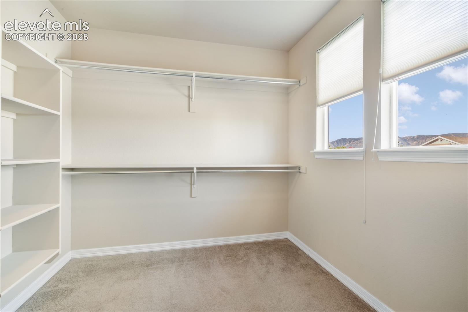 Built-in shelving, dual windows with blinds, and neutral carpeting