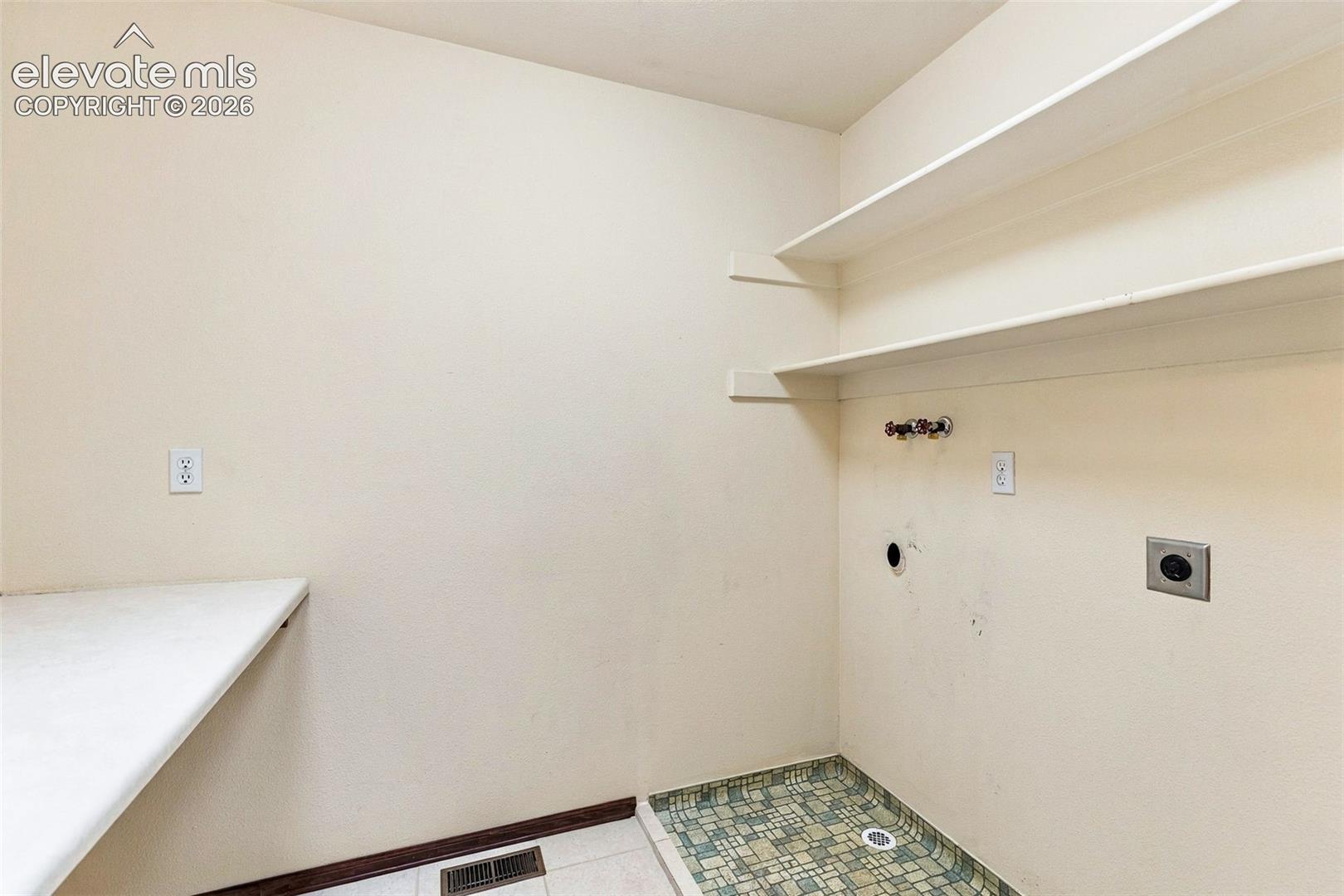 Upper level laundry with folding table and room for cabinets.