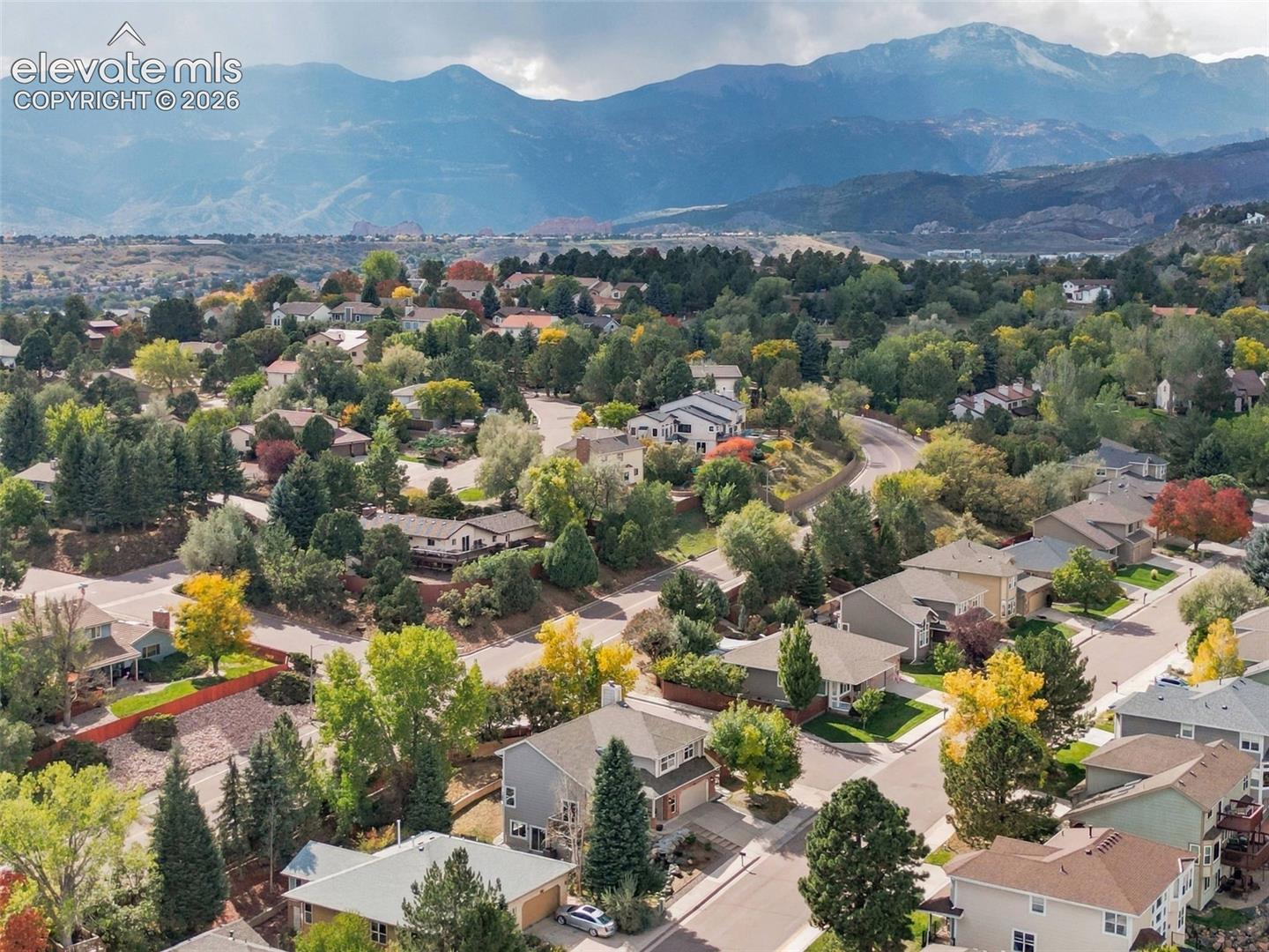 Residential area with mature trees, paved streets, and mountainous backdrop