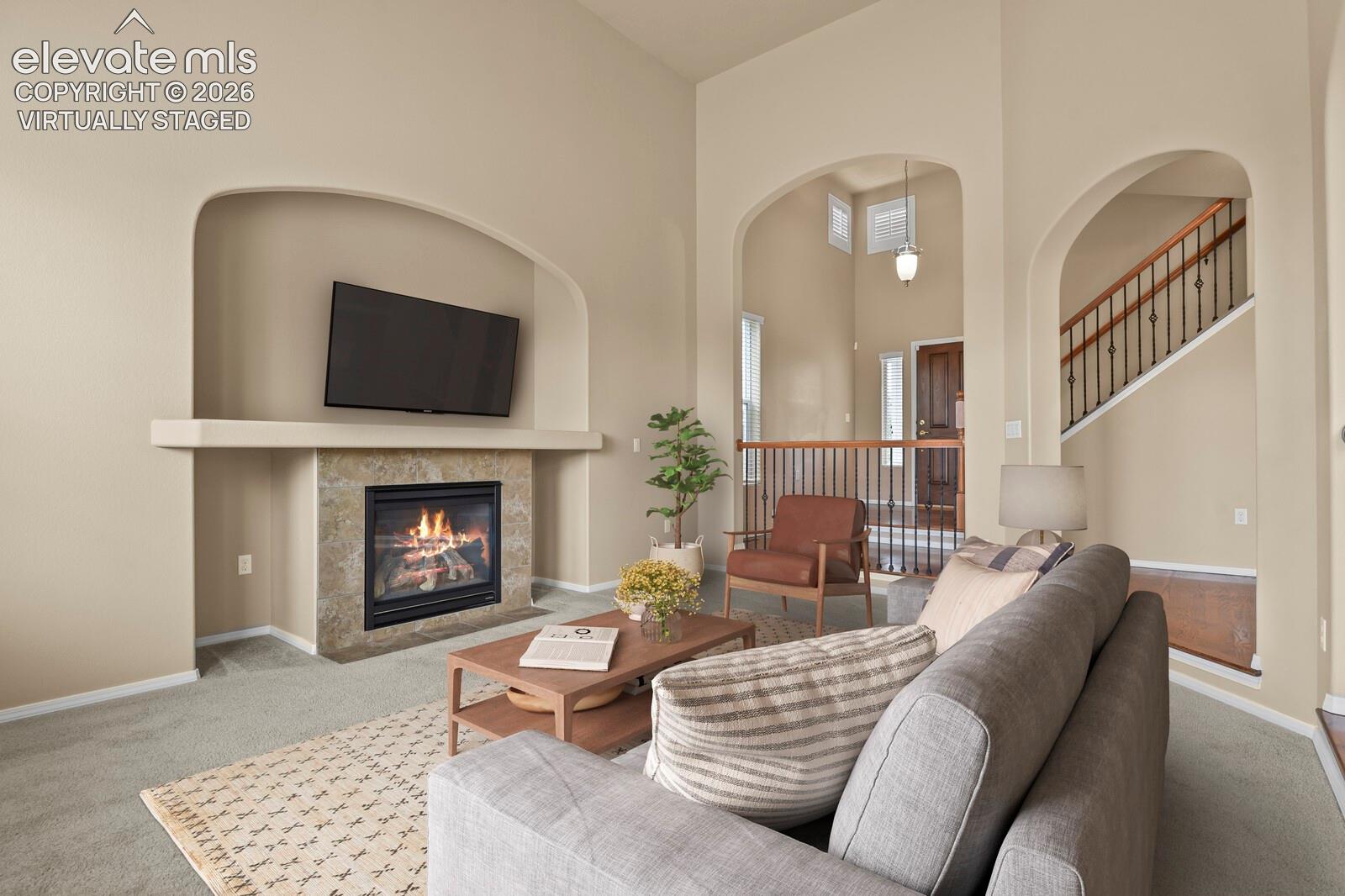 **Virtually Staged** Living room featuring a gas fireplace with a stone surround, a mantel, and built-in arched alcoves