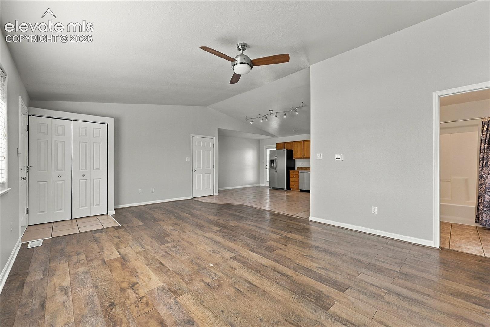 Interior space featuring vaulted ceilings, wood-finish flooring, and a ceiling fan