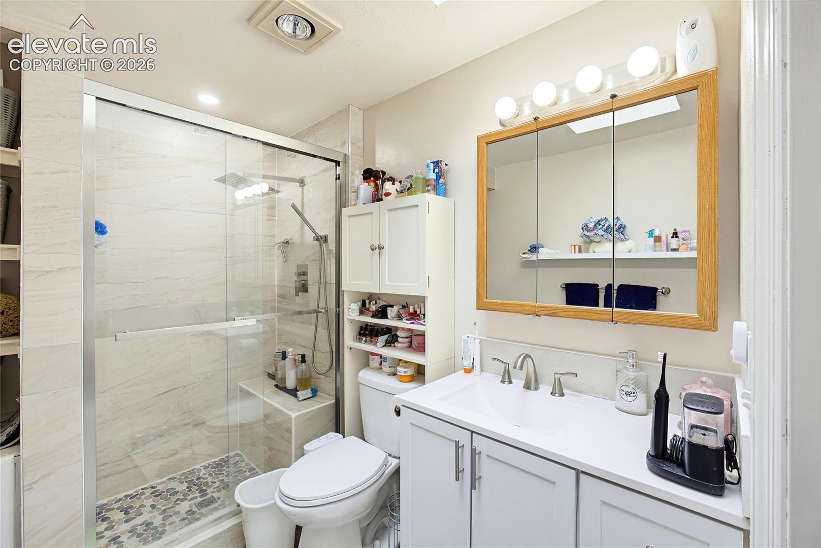 Glass-enclosed shower with stone tile surround and built-in bench