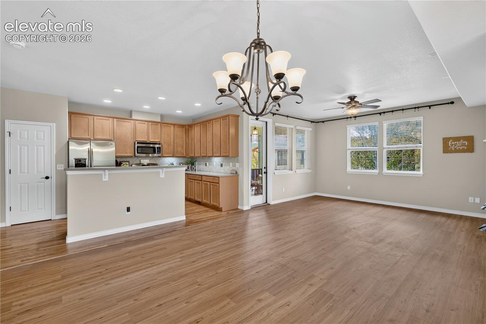 Open-concept with luxury vinyl and natural wood flooring, a kitchen, chandelier for dining area, recessed lighting, and a ceiling fan, walkout to covered Patio