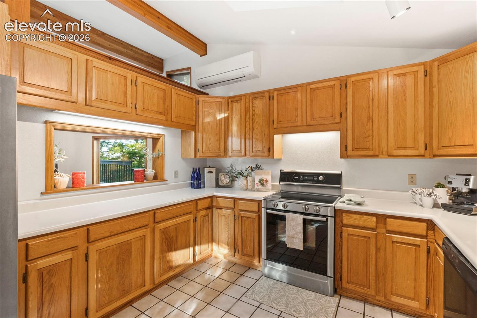 Kitchen featuring natural wood cabinetry, white countertops, ceramic tile flooring, exposed structural ceiling beams, and a stainless steel slide-in range