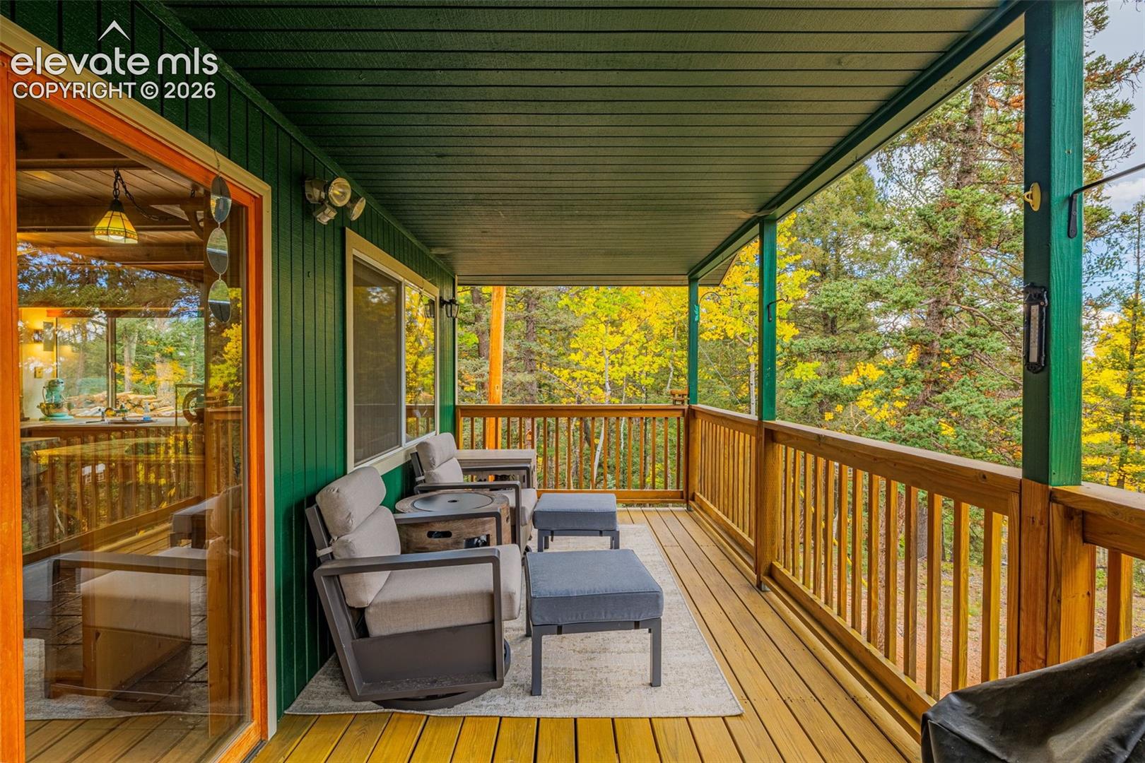 Covered deck featuring wood-finish flooring, vertical panel siding, and a wooden balustrade