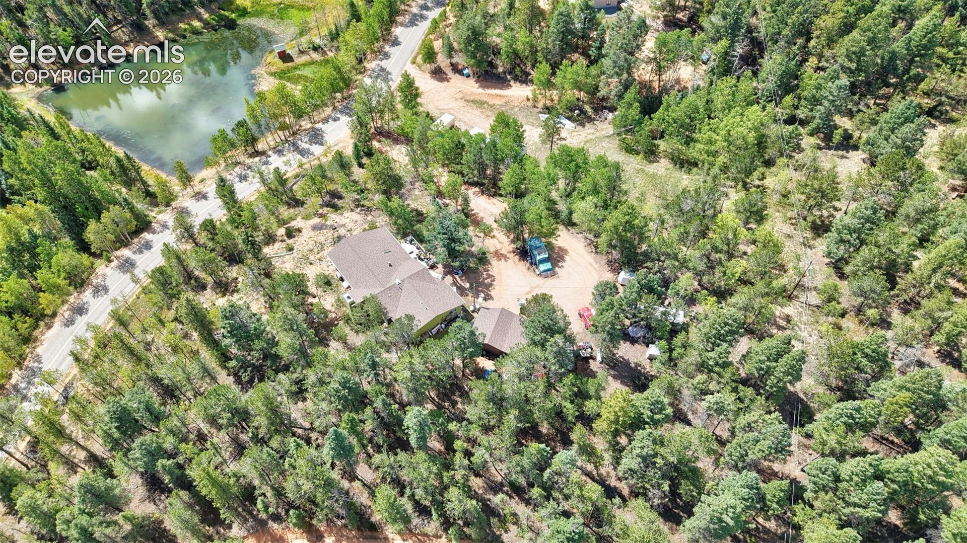 Property surrounded by mature trees, with a natural water feature