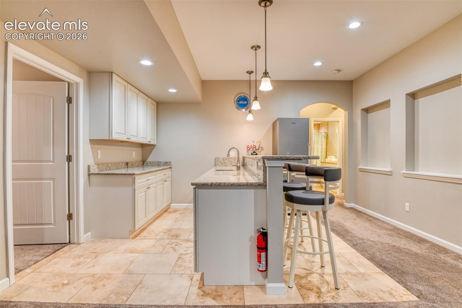 Bar area featuring white cabinetry, granite countertops, and a tile floor.