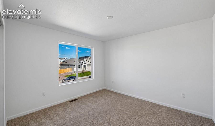 Neutral-toned carpeted flooring, white wall finishes, and a single-pane window featuring exterior neighborhood exposure
