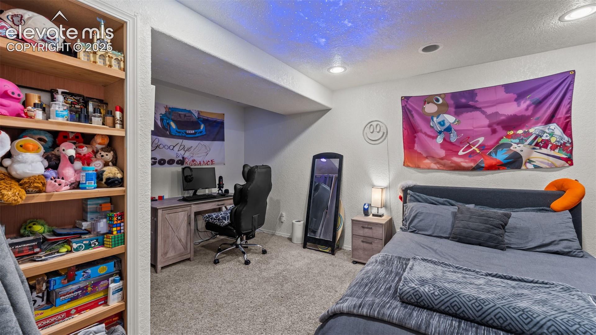 Built-in shelving, recessed lighting, carpeted flooring, and a desk area