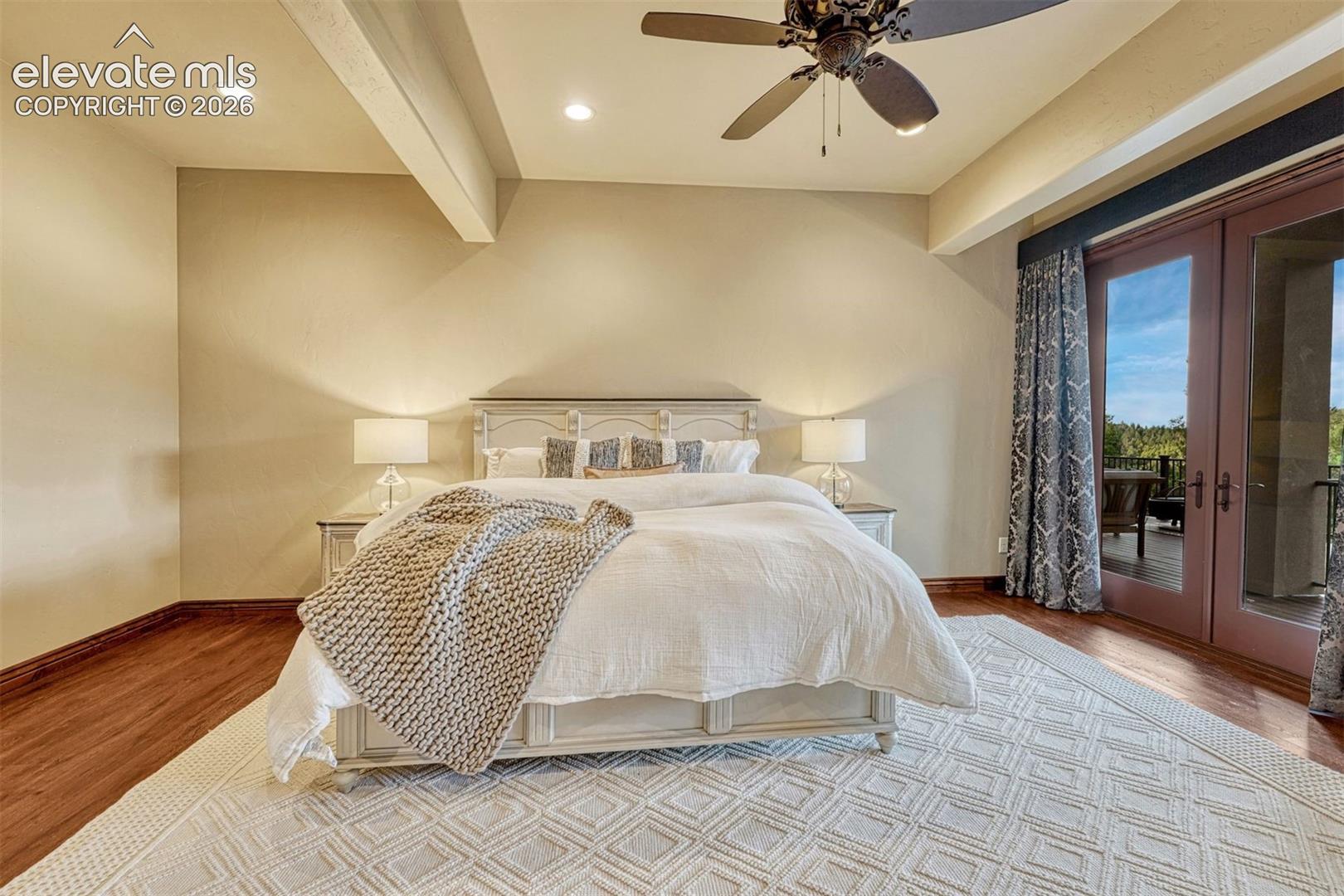 Wood-finish flooring with an area rug, ceiling fan, recessed lighting, and balcony access through double doors