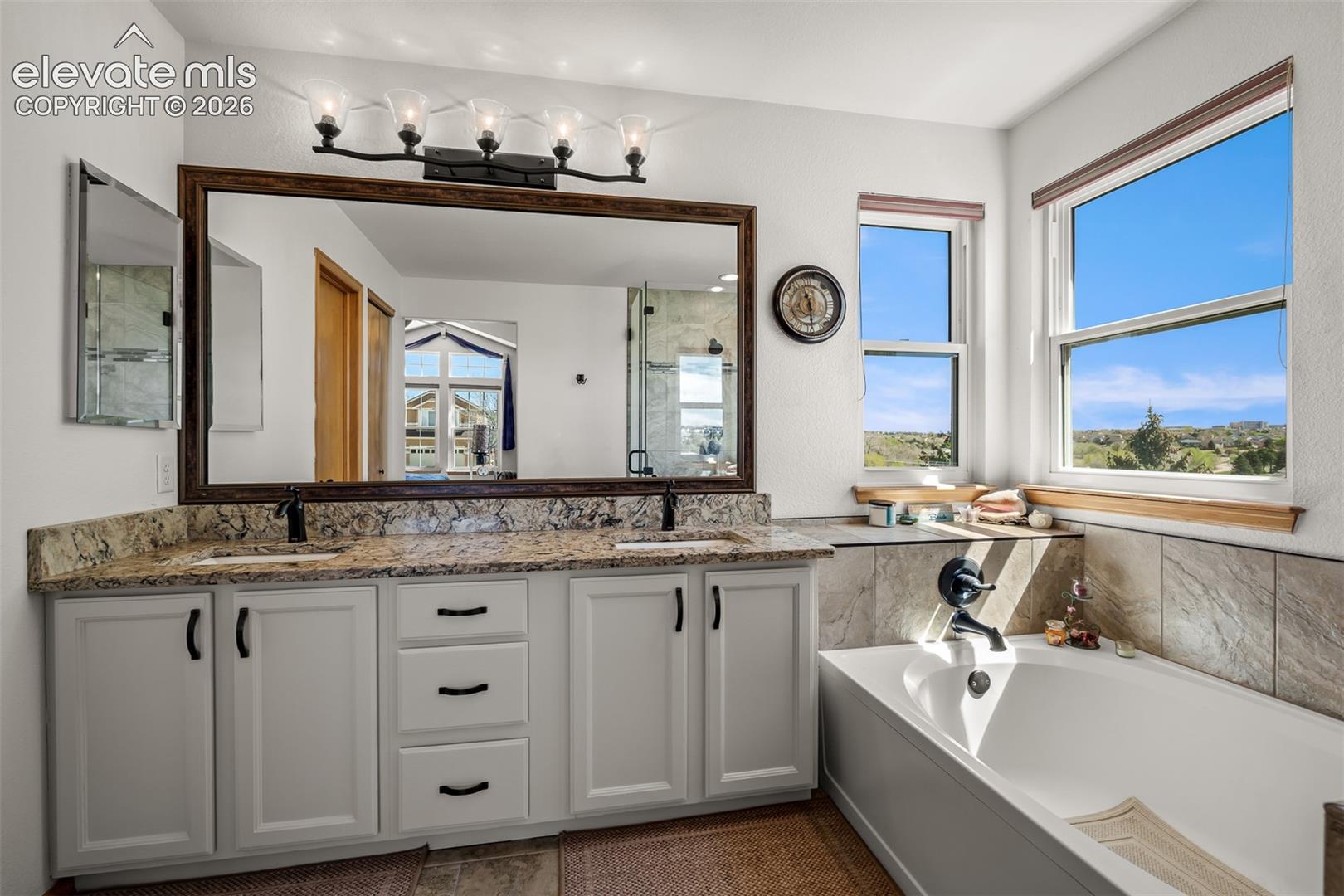 Double vanity with quartz countertops, dual under-mount sinks, and matte black fixtures.   Lots of natural light.