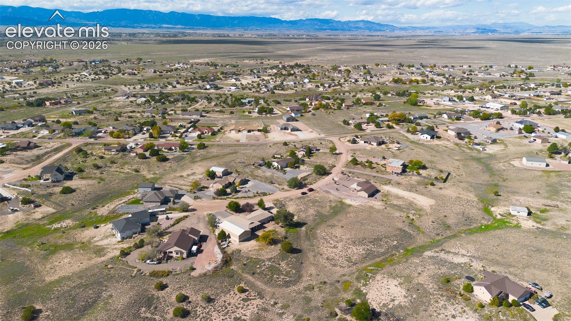 Aerial perspective showcasing expansive terrain with mountain range backdrops and residential development