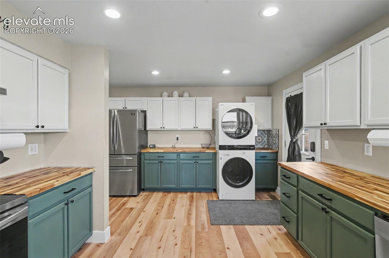 Two-toned cabinetry with butcher block countertops, wood-finish flooring, stainless steel appliances, and recessed lighting