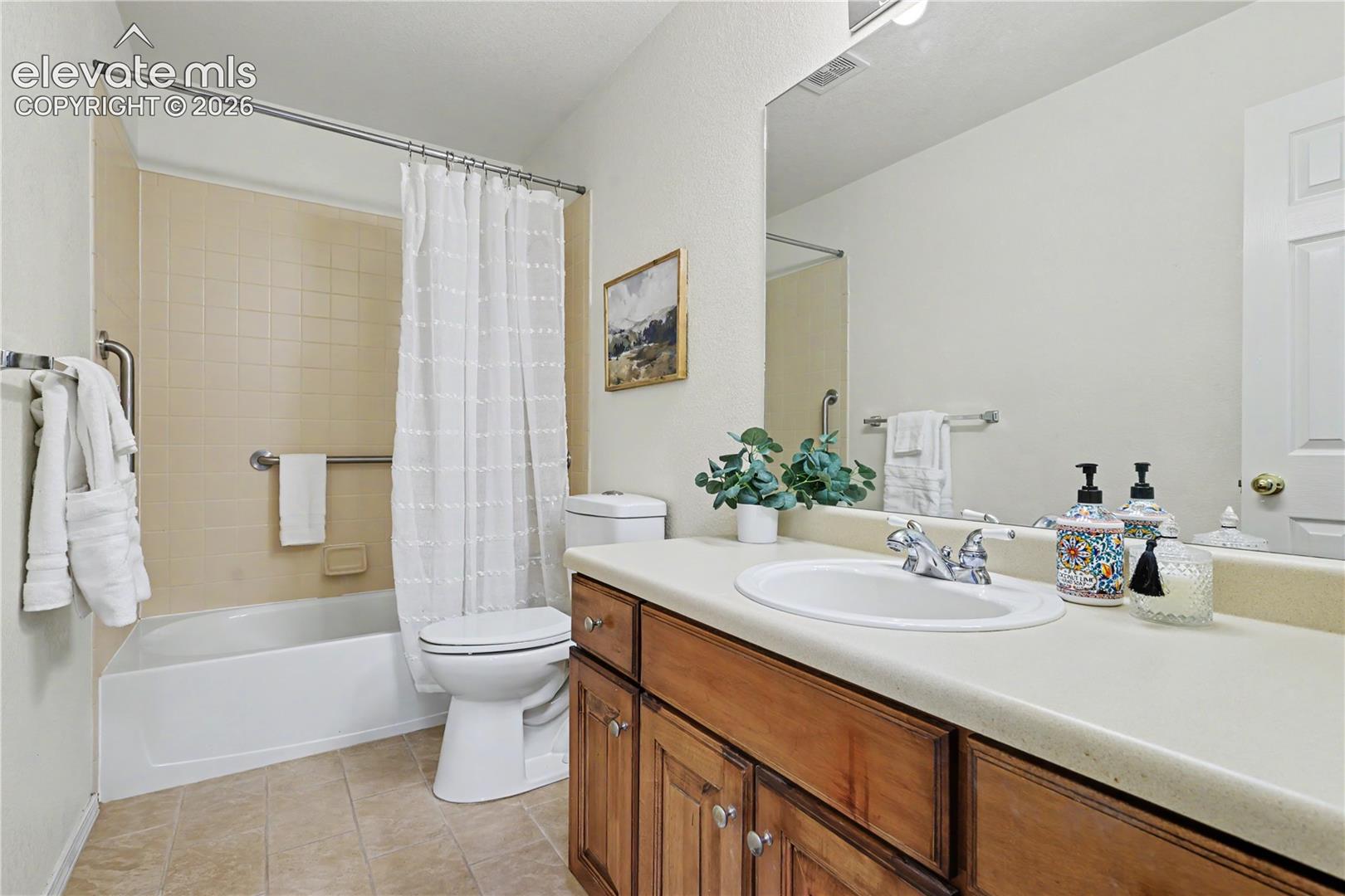 Bathroom featuring a full vanity with wood-finish cabinetry, an integrated sink, and a large wall-mounted mirror