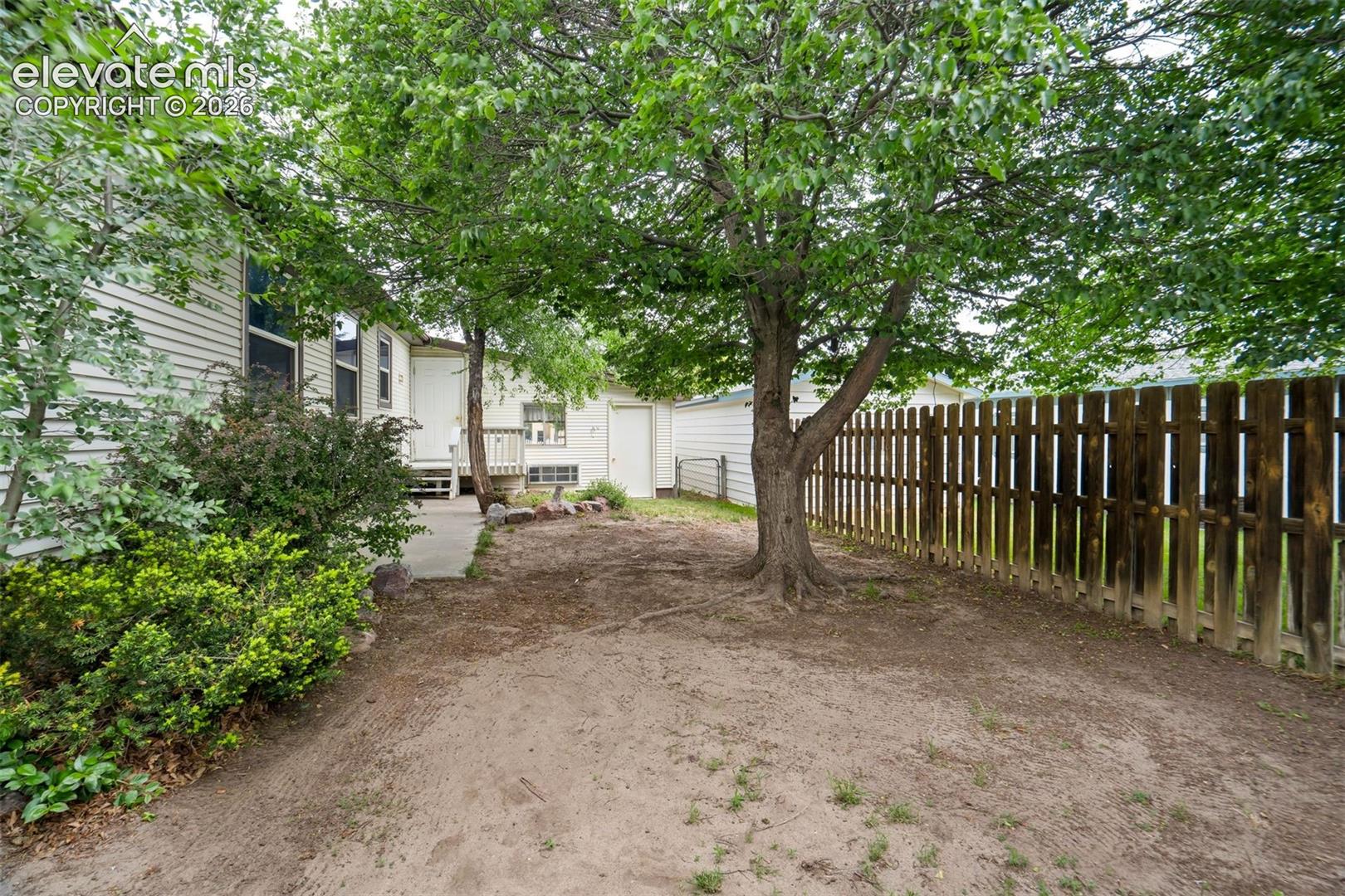 Fenced backyard with mature trees providing shade and privacy.