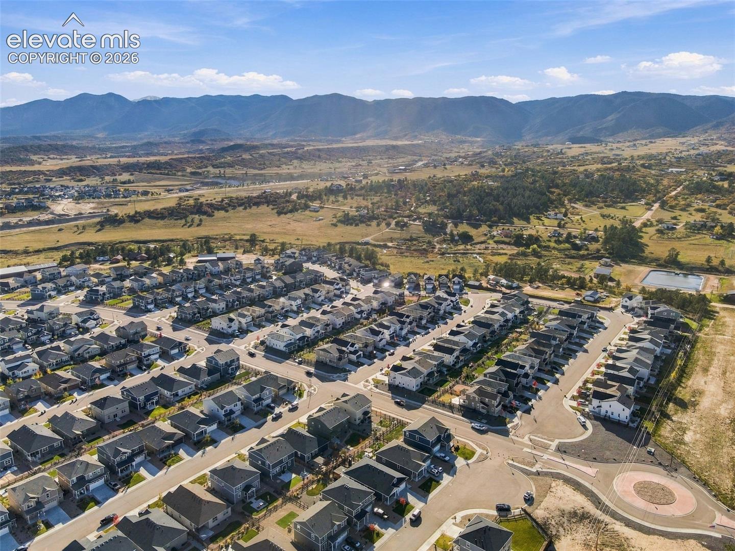Aerial perspective featuring a multi-parcel neighborhood development with asphalt street infrastructure, cul-de-sacs, and a backdrop of expansive mountain topography