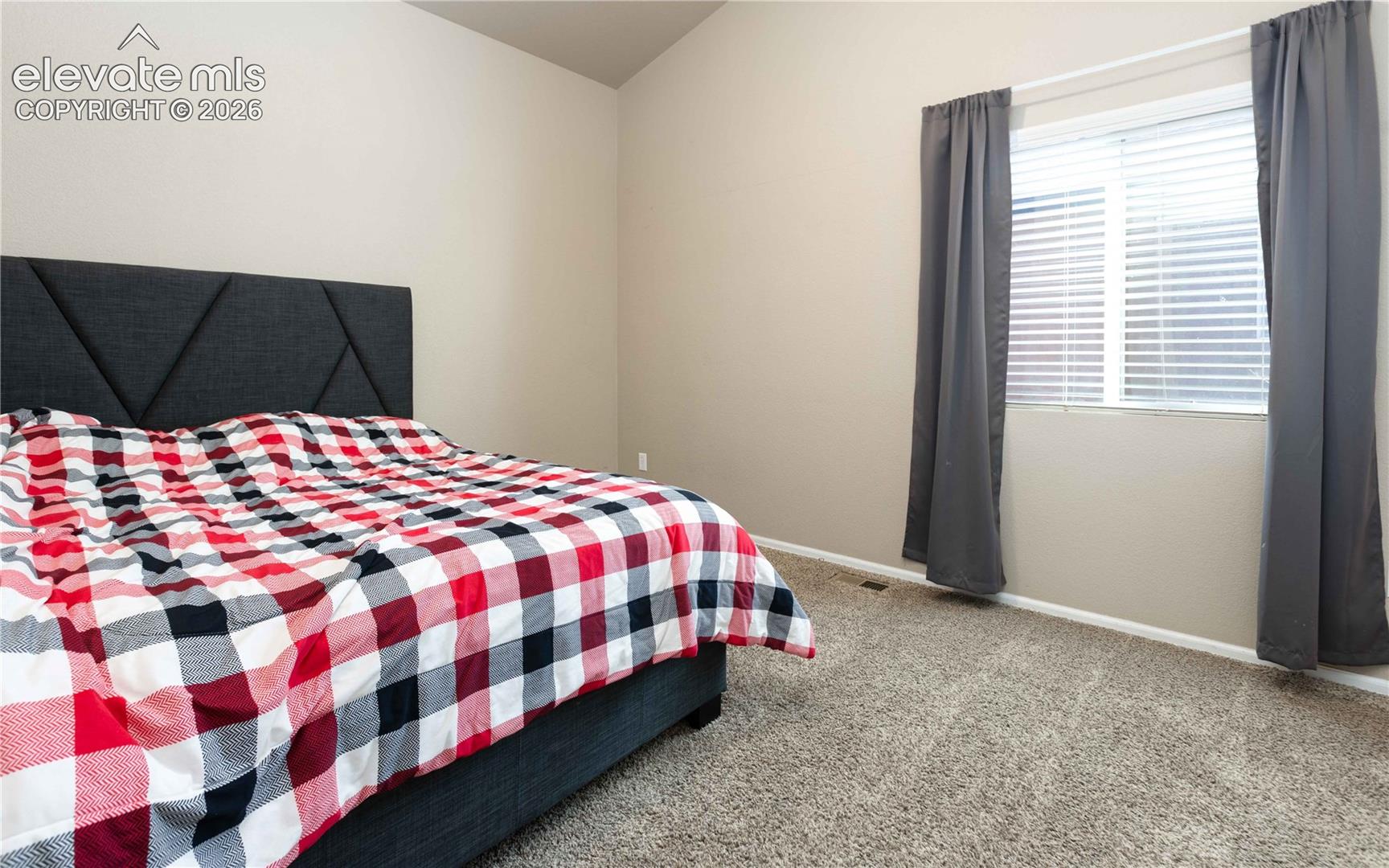 Room featuring vaulted ceilings, neutral wall tones, and carpeted flooring
