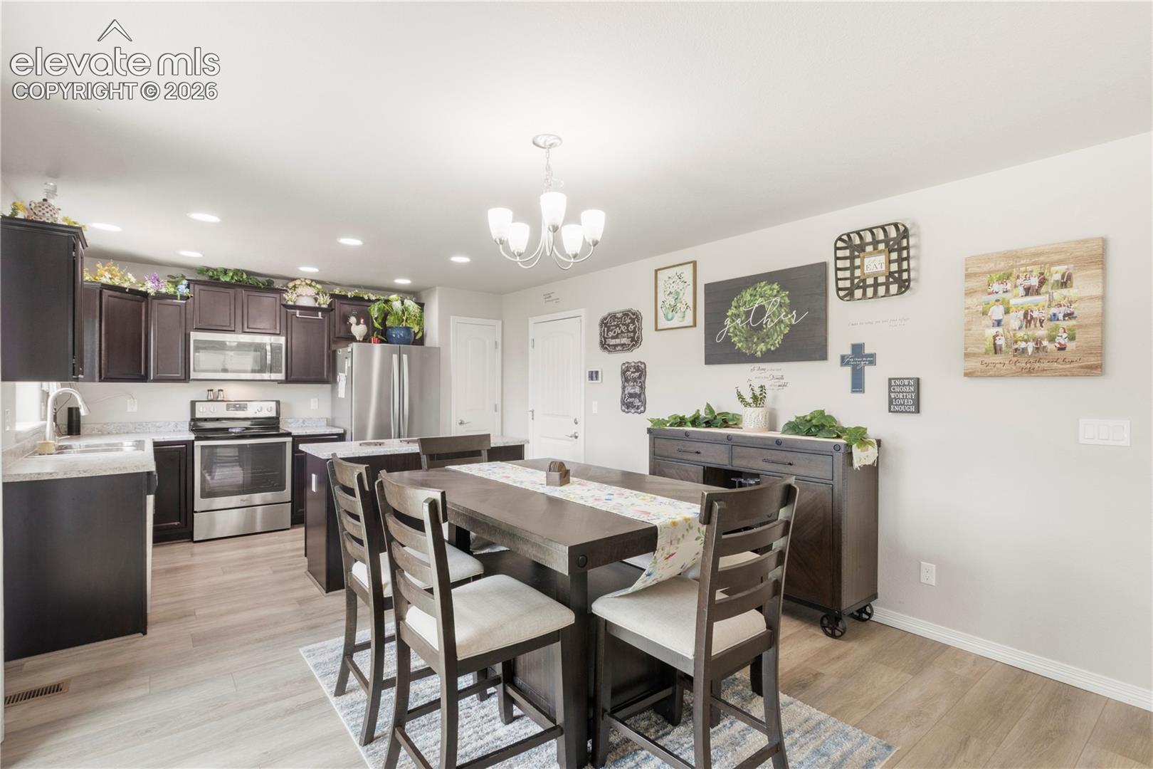 Kitchen featuring wood-finish flooring, dark wood cabinetry, light-toned countertops, and stainless steel appliances