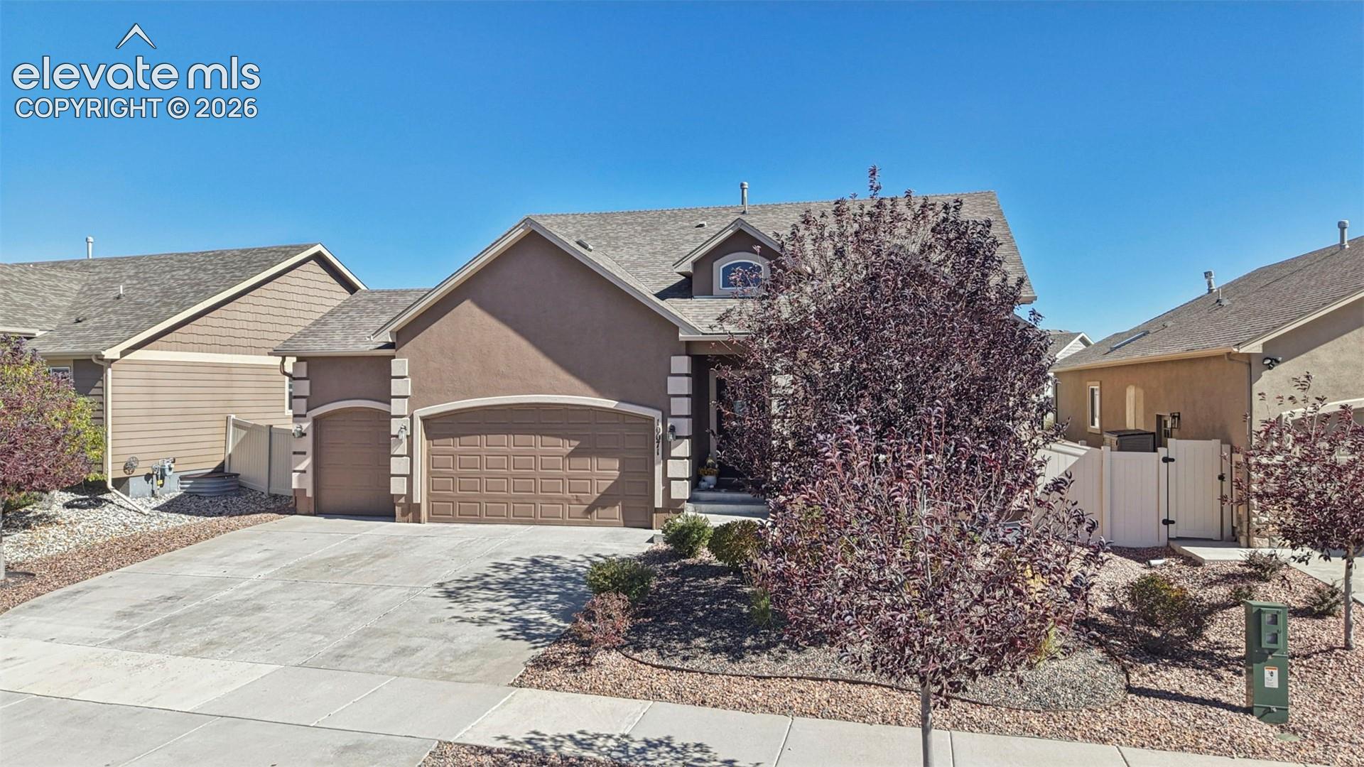 Stucco exterior featuring arched garage openings, quoined corner detailing, and an arched architectural window gable