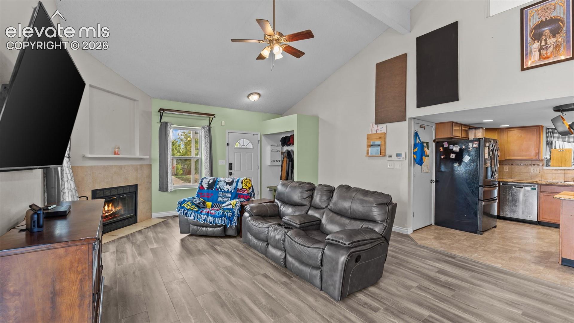 Vaulted ceilings, wood-finish flooring, and a fireplace with a stone-tile surround